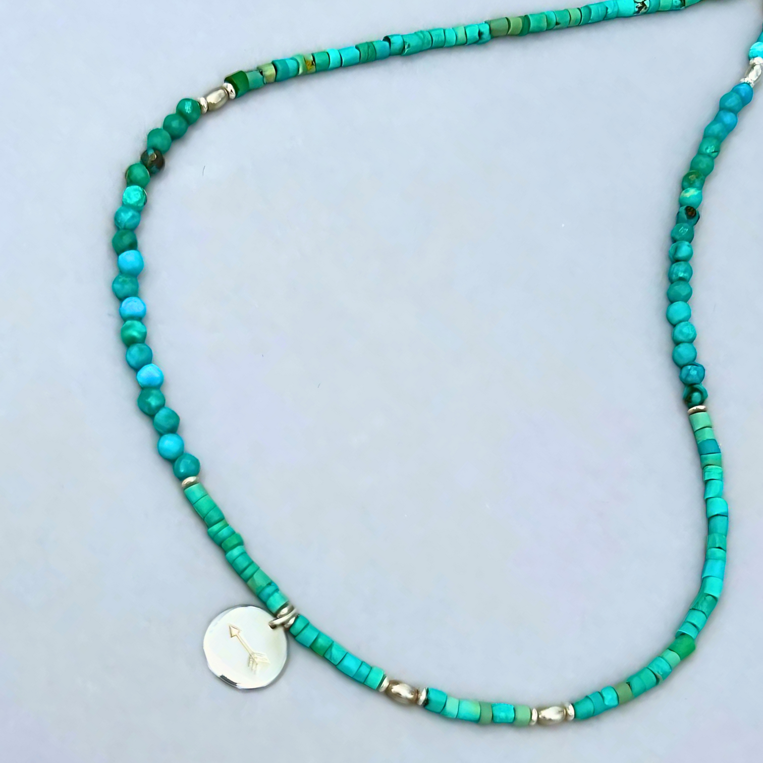 Free Spirit Necklace from Le BijouBIjou made with turquoise rondelles and a silver charm with an arrow. Detail of Cham and turquoises.