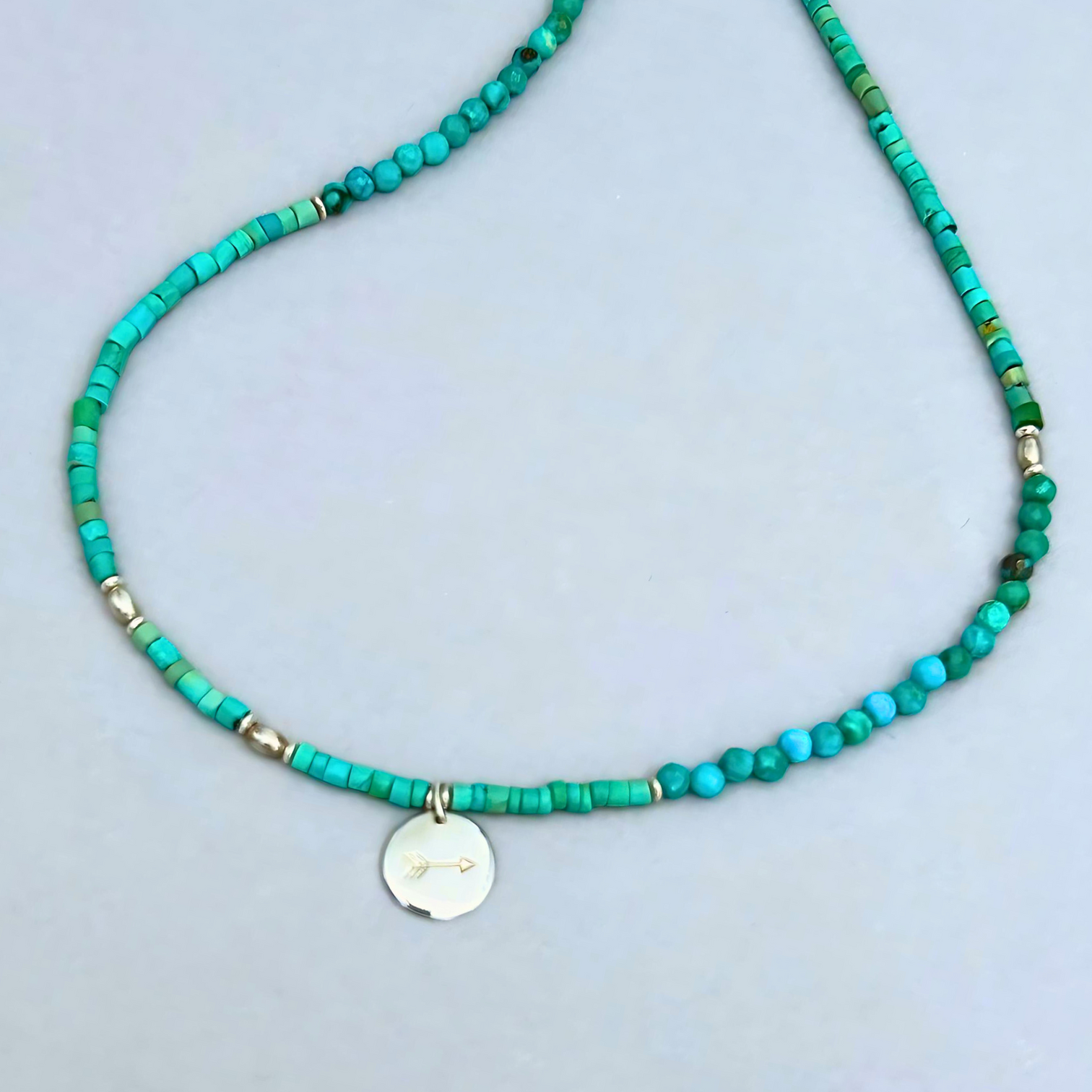 Free Spirit Necklace from Le BijouBIjou made with turquoise rondelles and a silver charm with an arrow. Close-up picture.